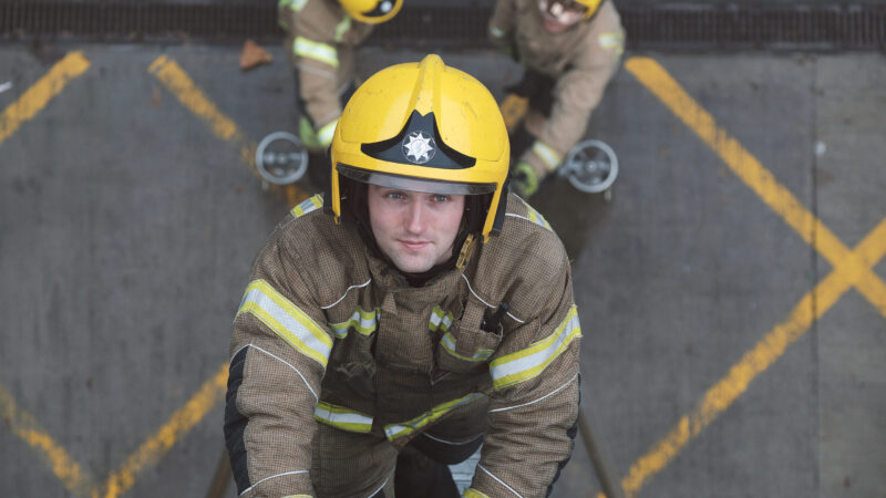 White male Firefighter climbing ladder in full kit