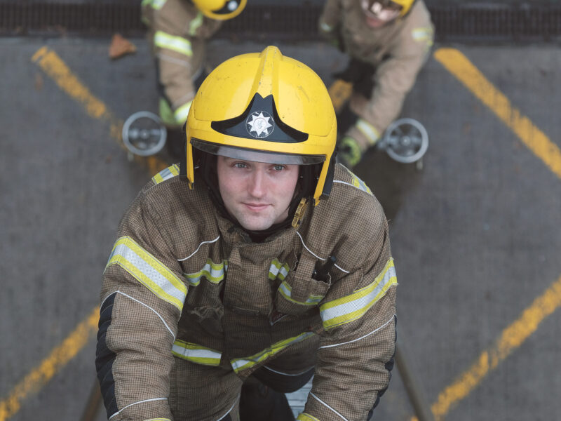 White male Firefighter climbing ladder in full kit