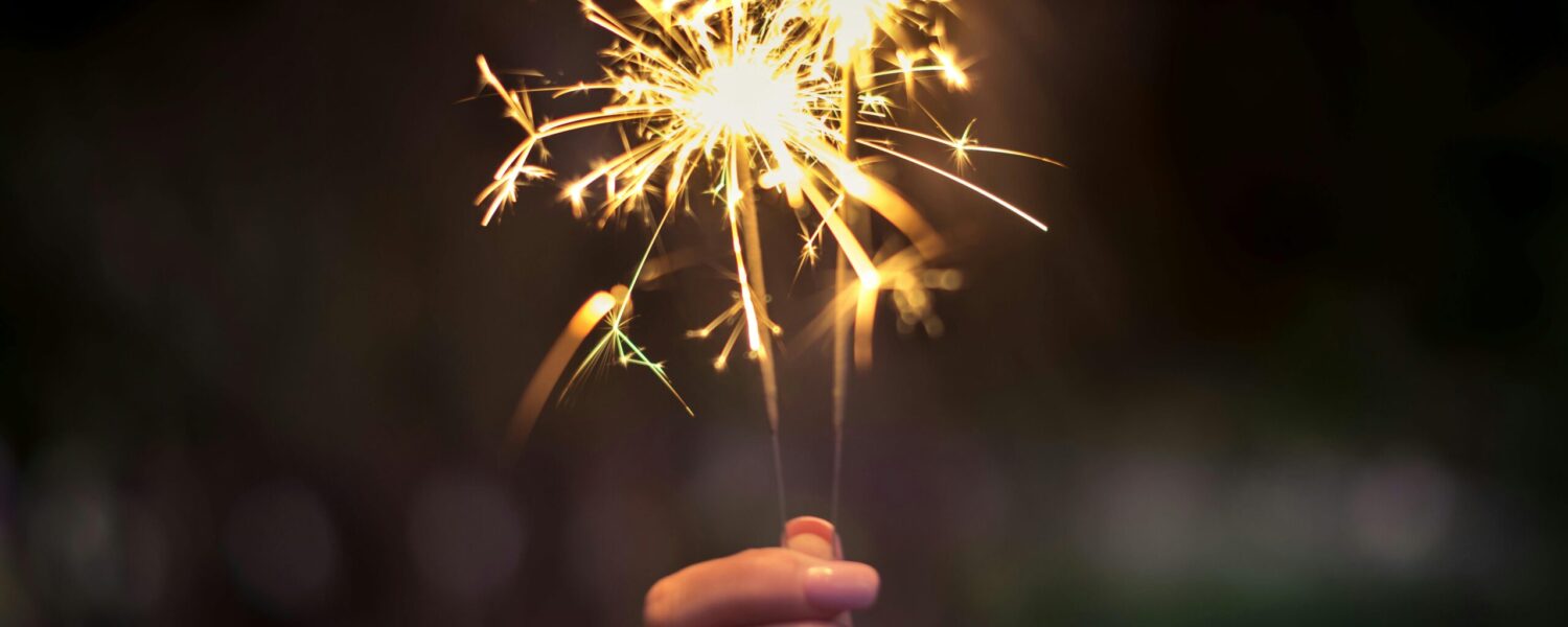 Hand holding two lit sparklers