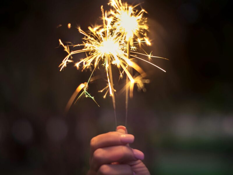 Hand holding two lit sparklers