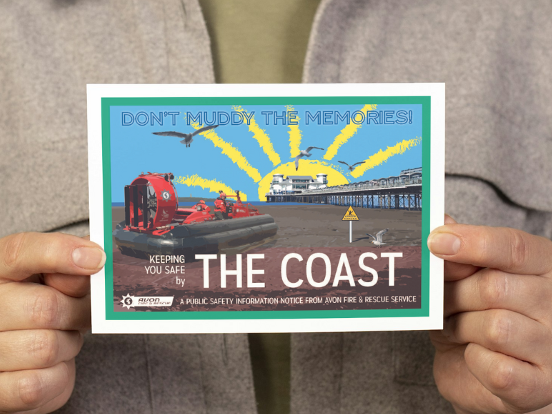 person holding postcard with vintage themed design that says 'don't muddy the memories' and ';keeping you safe by the coast' with an image of a fire service hovercraft on Weston-super-Mare beachfront