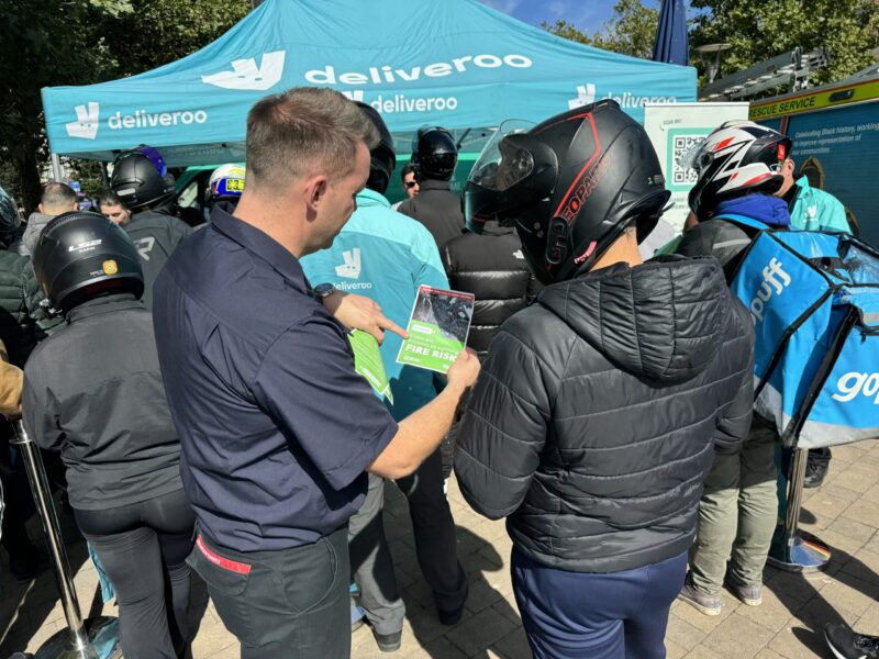 Firefighter giving charge safety advice to a Deliveroo rider